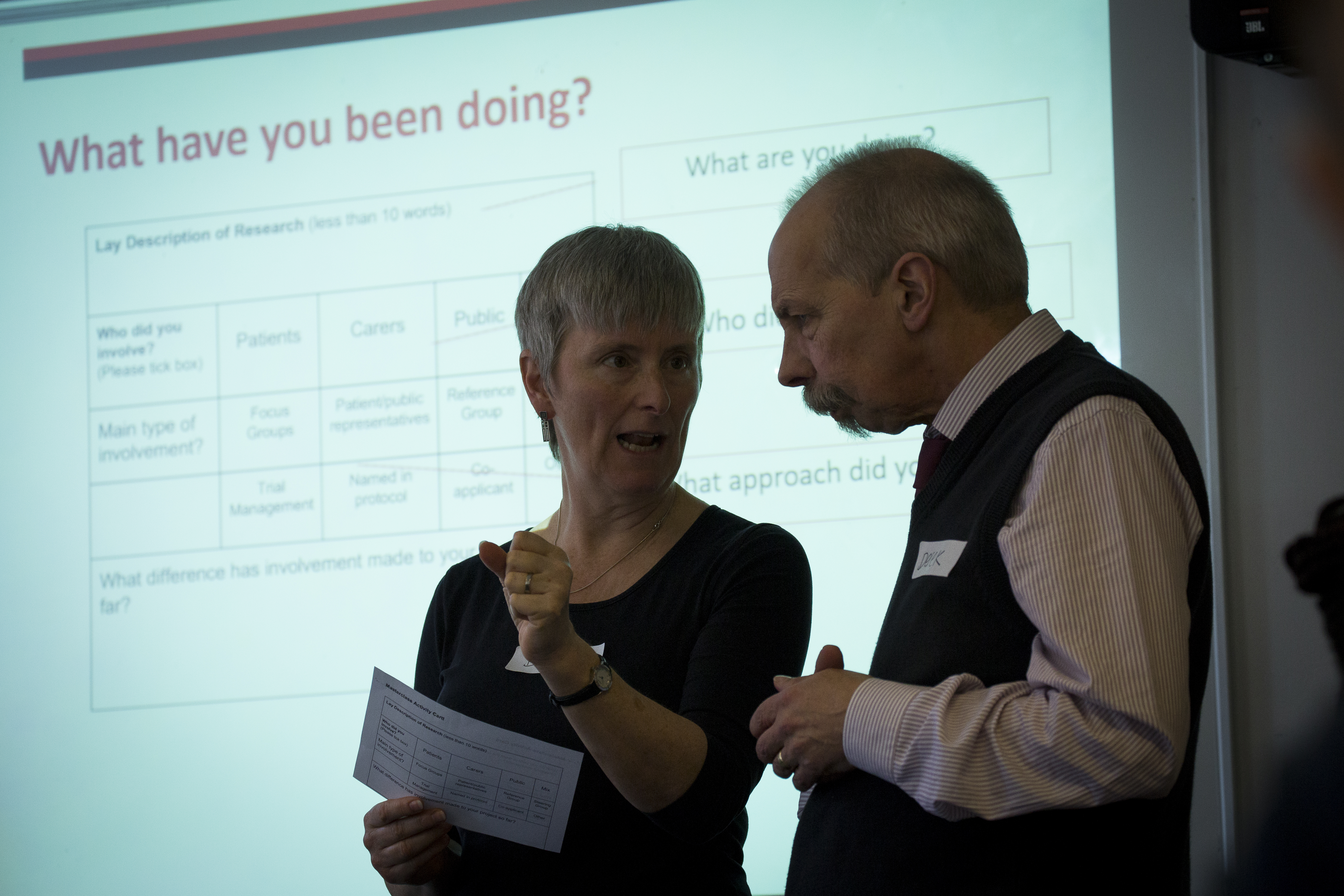 Two individuals in front of screen talking to each other